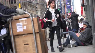 Image of homeless man being ignored on the street by people passing by.