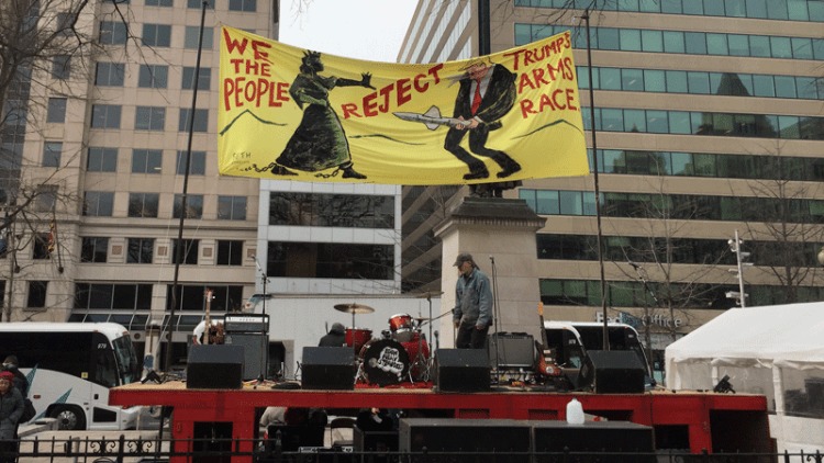 sign above protesters' stage at franklin square park that reads "we the people reject trump's arm race"