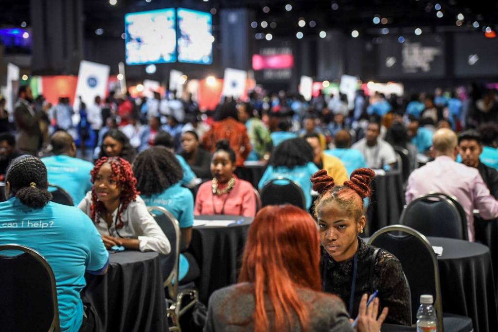 Job seekers practice interviewing with volunteers in blue shirts
