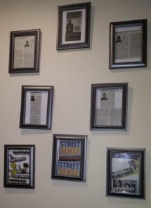 Several framed articles written by Marcellus Phillips hang on his apartment wall. hang on a w