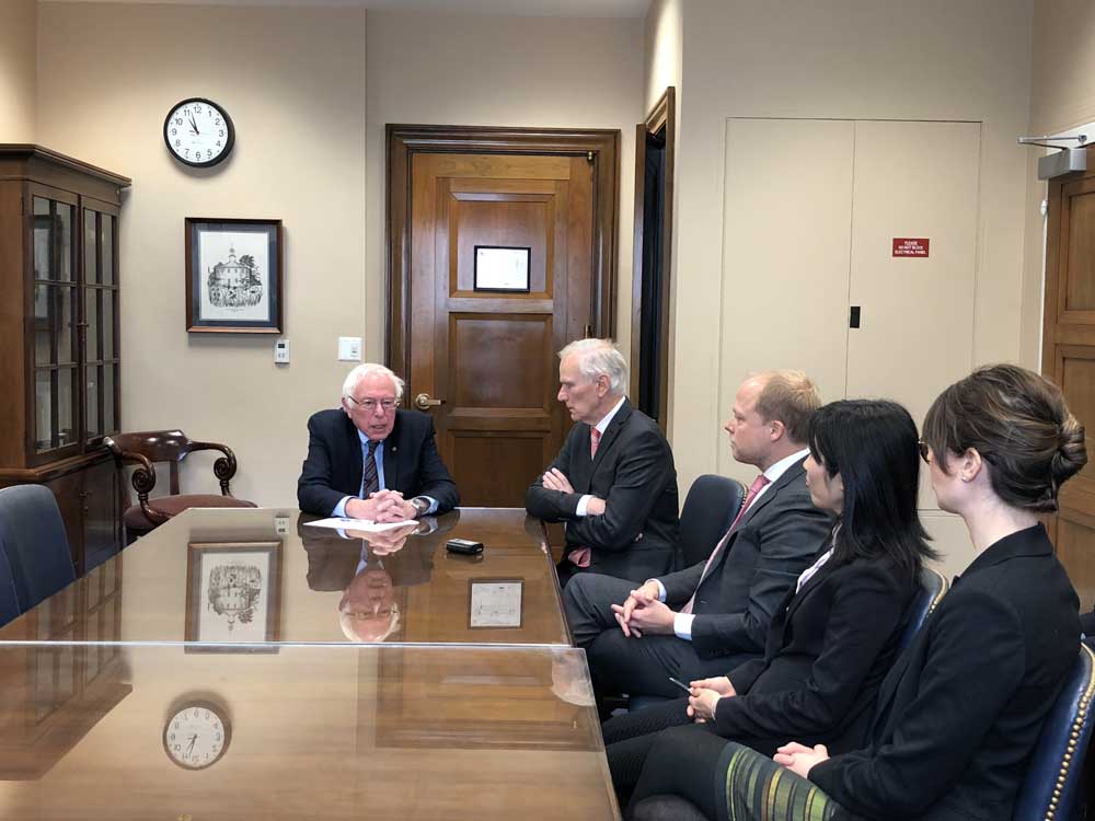 Bernie Sanders, Philip Alston and members of his team from the U.N. sit at a conference table together.
