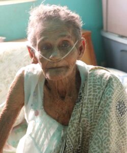 An elderly woman with a breathing tube in her nose.