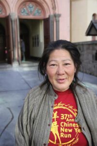 A woman in a green jacket and red shirt.