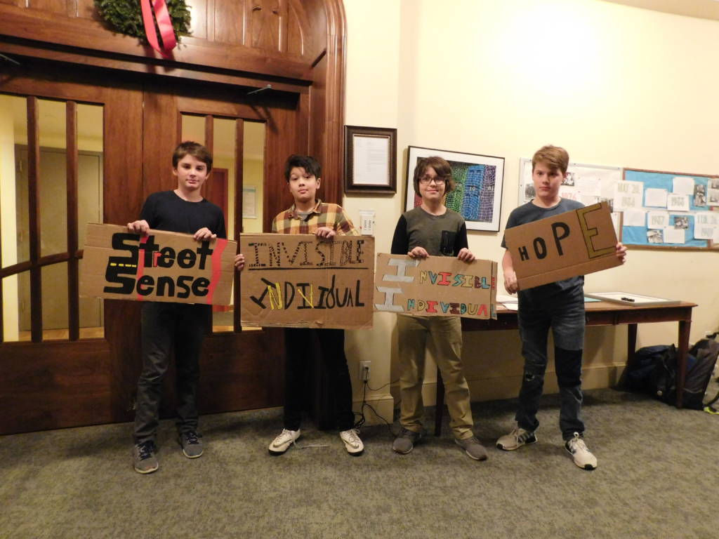 Photo of four young kids holding cardboard signs.
