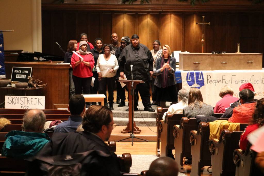 Photo of a choir at the front of a sanctuary, with people seated in the audience.