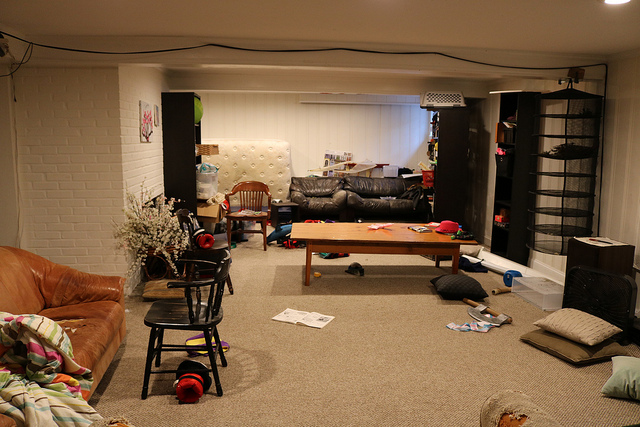 A photo of a living room with chairs, couches, and children's toys.