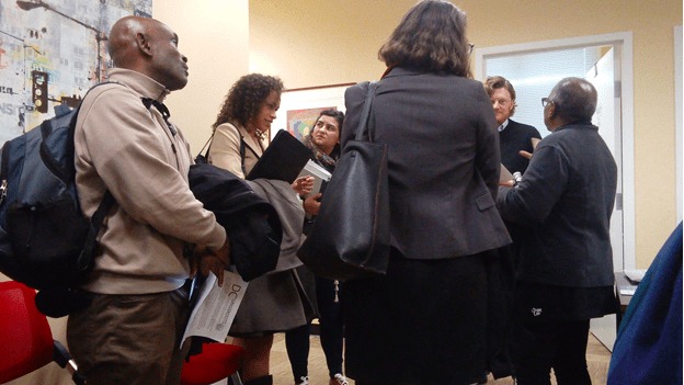 Color photo of a group of people gathered in a room and visiting with a staff member of Ward 5 Councilmember Kenyan McDuffie