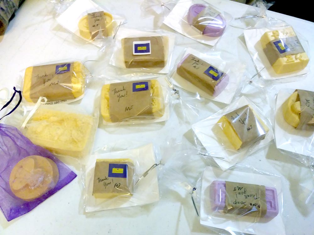 Photo of many packaged bars of yellow and purple soap on a tabletop.