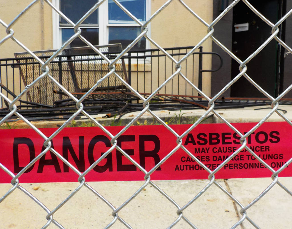 Photo of a red warning tape with the words "DANGER" printed on it, stretched across the fence surrounding a housing unit.