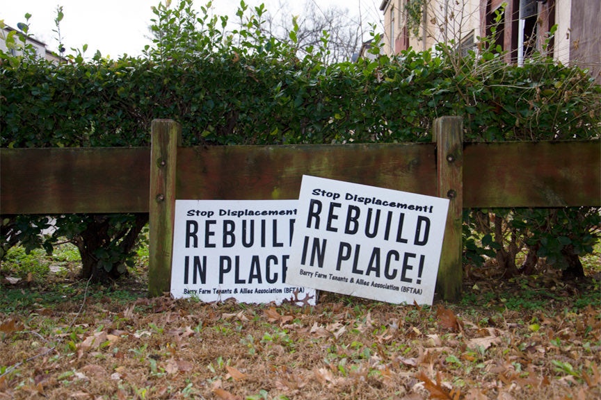 Photo showing two signs sitting in a yard. Both say "REBUILD IN PLACE!"
