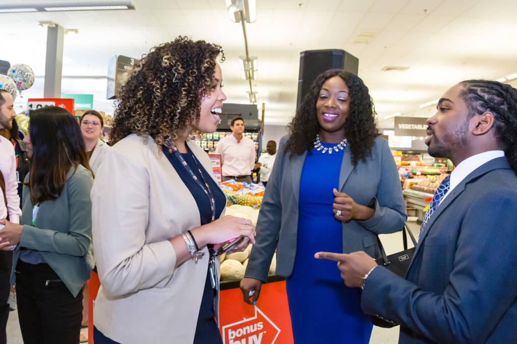 Photo of three people talking in a grocery aisle.