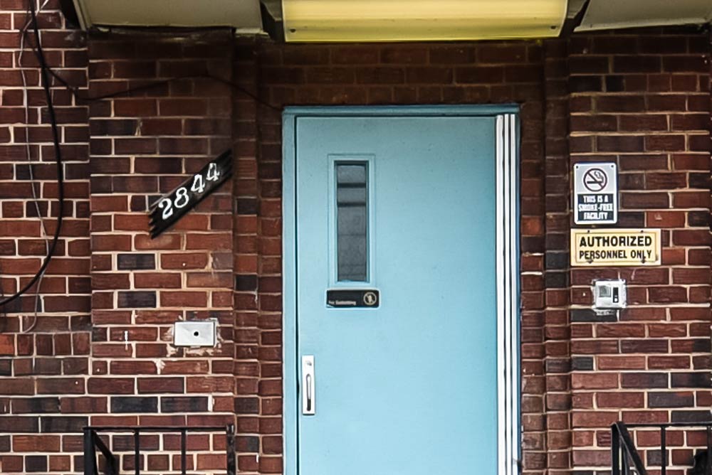 Photo of the door to one of the several buildings that make up Hope Village. Several signs, including "Authorize Personnel Only," are visible.