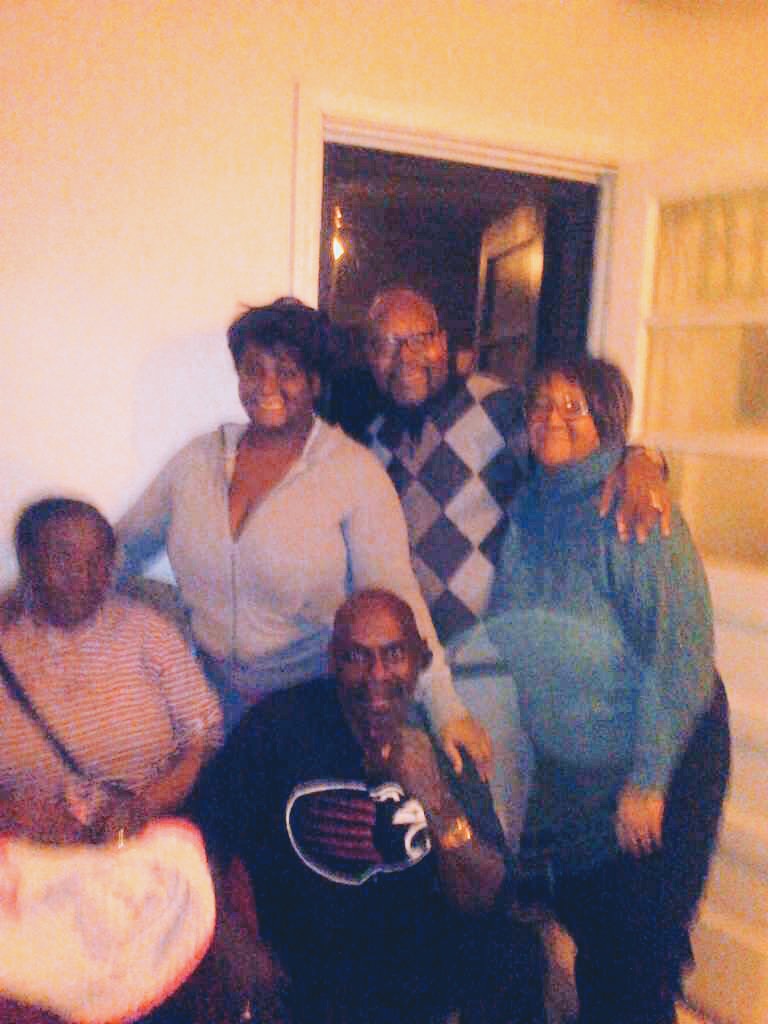 Photo of five people smiling together indoors.