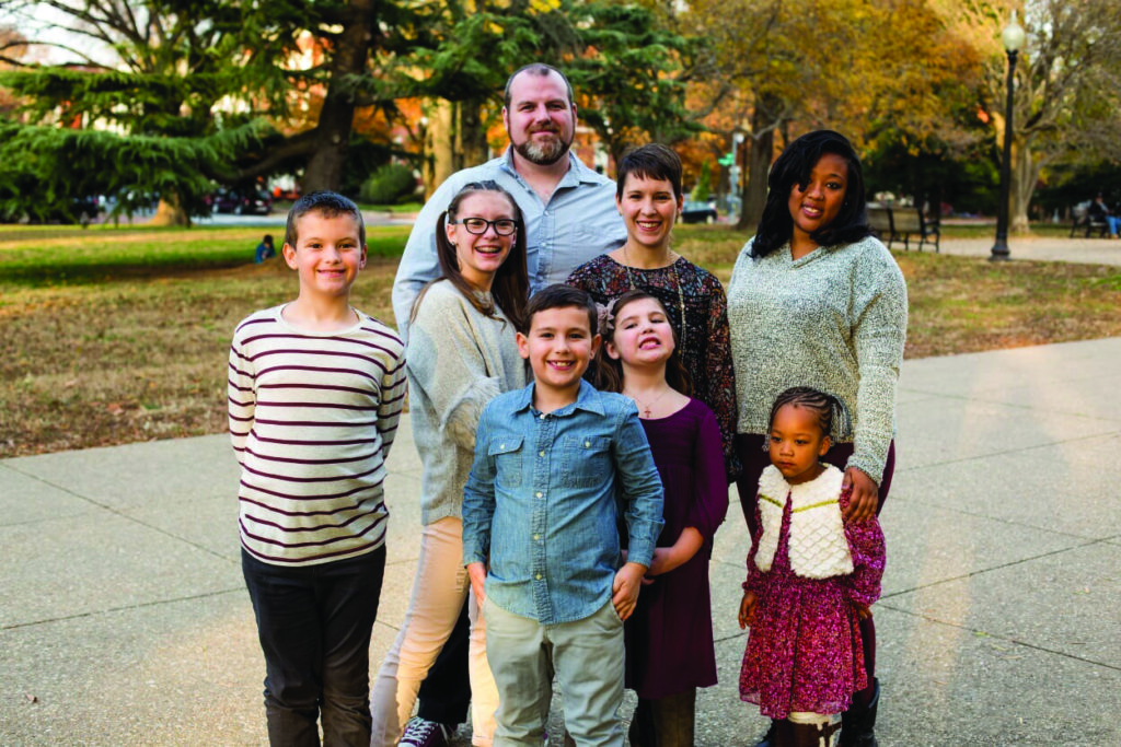 A family stands outside with a mother and daughter they helped through a foster care prevention program.
