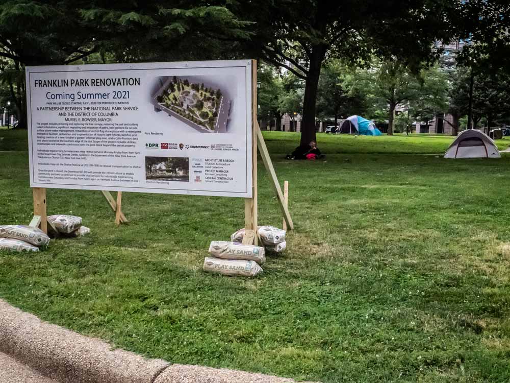 Photo of a sign reading "Franklin Park Renovation coming in Summer 2021," with two tents visible in the park behind it.