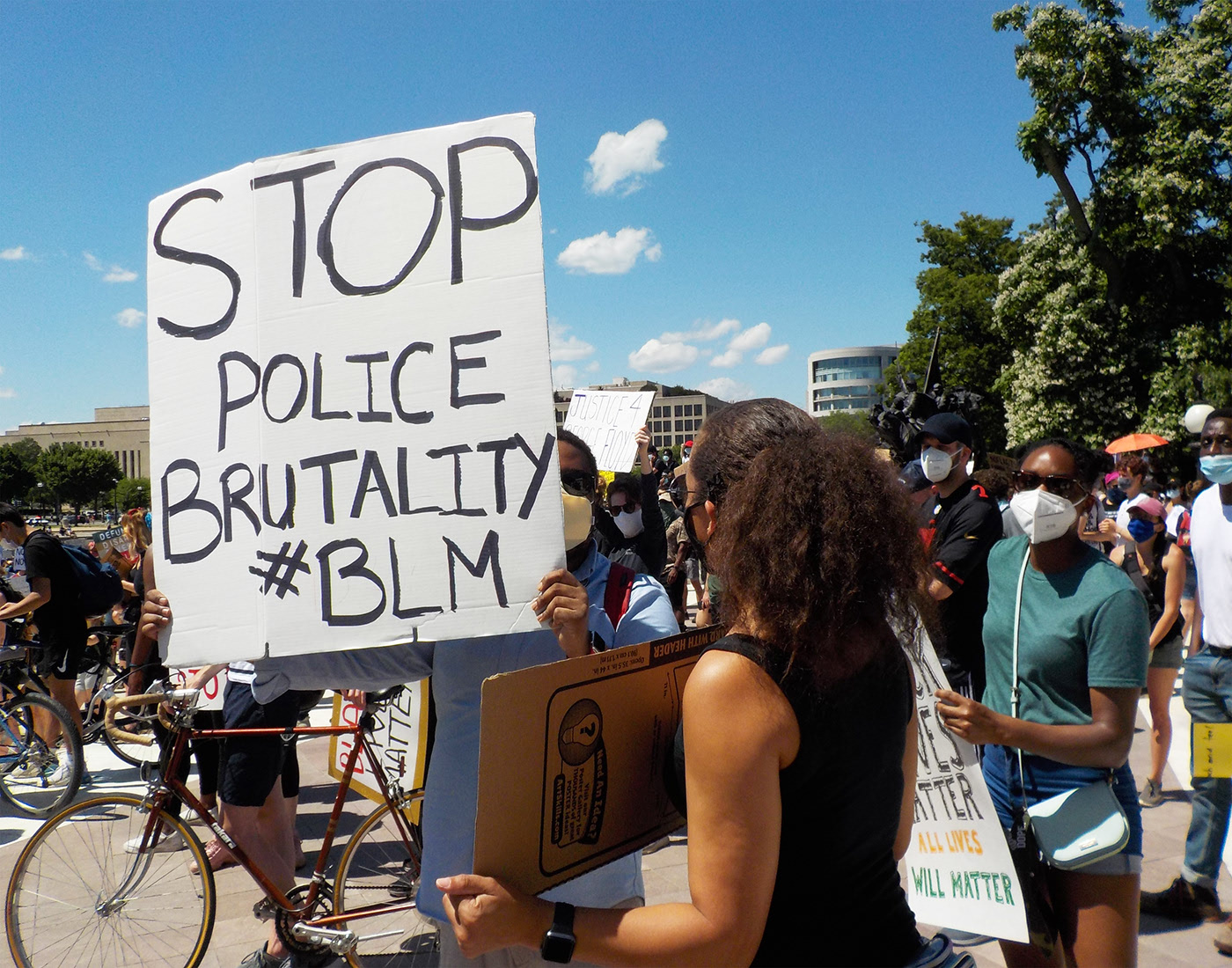 Protester holding a sign reading "Stop Police Brutality #BLM"