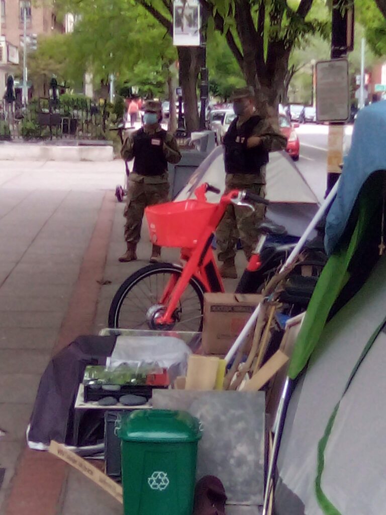 Photo showing two national guard soliders in uniform standing between Stevie and Savon's tent and another tent.