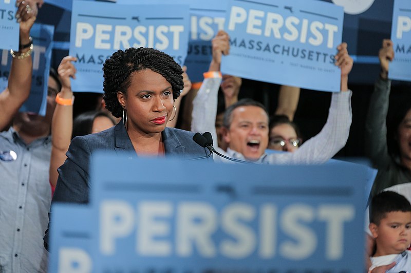 A Black woman in a sea of campaign signs.