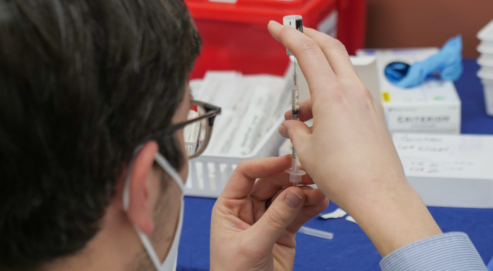 Image showing a person preparing a vaccine. Perspective is from behind the subject
