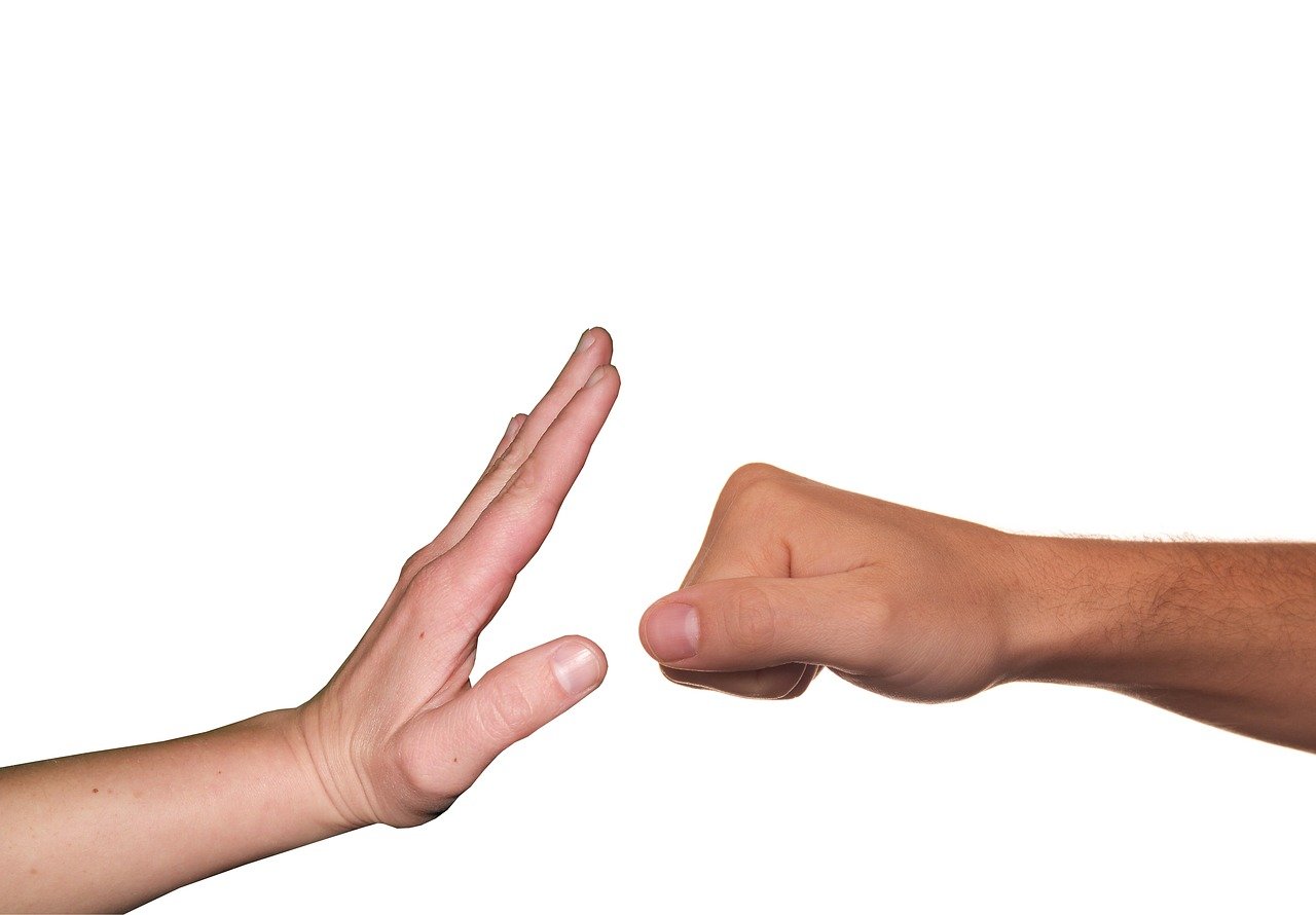 Image of a hand stopping another hand that is raised in a fist