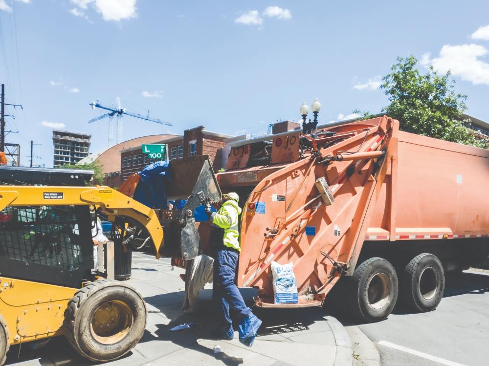 Heavy machinery is used to fill a garbage truck with items left behind in the encampments