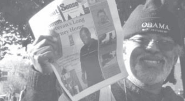 Warren Stevens, Jr holding up a copy of Street Sense for sale.