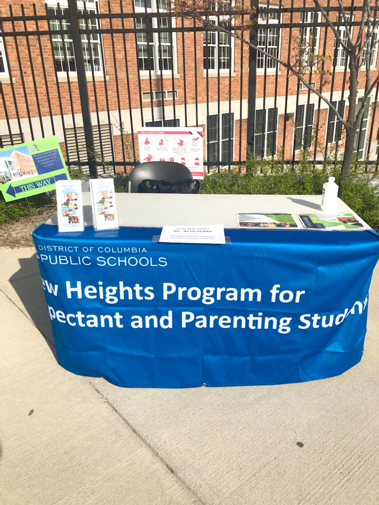 Photo of a table with a banner that says "DCPS: The New Heights Program for Expectant and Parenting Students"