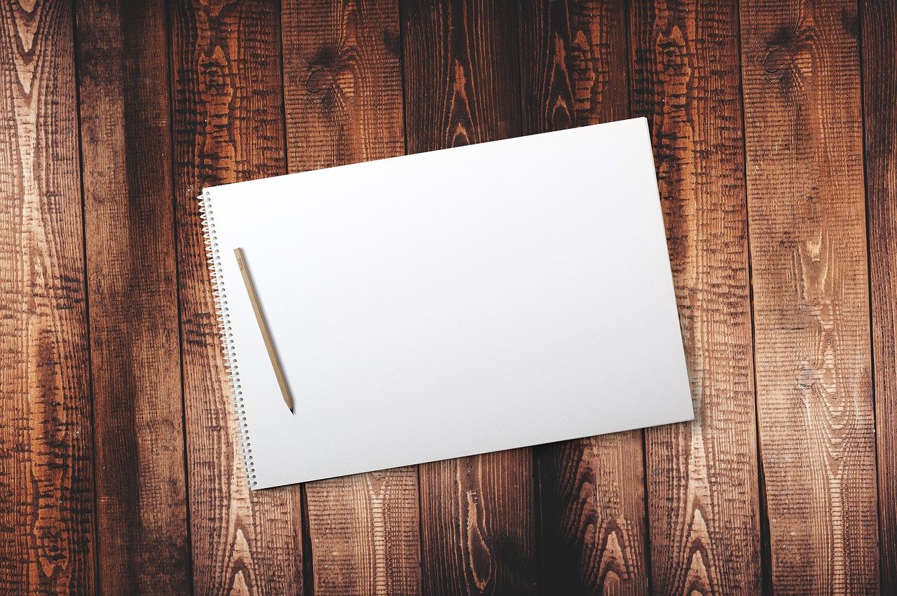 Photo of blank pad of paper an a pencil sitting on a otherwise empty desk.