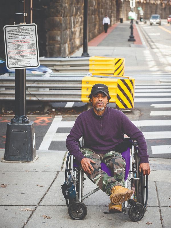 Michael Harris moves down the sidewalk in his wheel chair. The eviction notice for the encampment is right behind him.