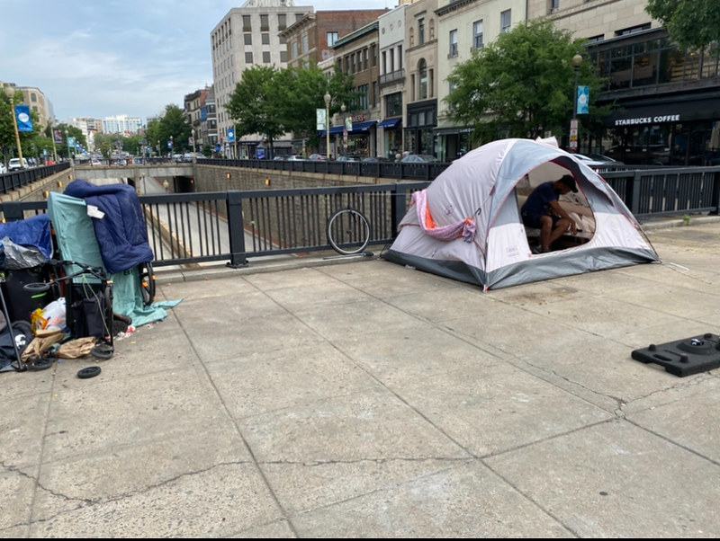 A man reorganizes his belongings after setting his tent back up.