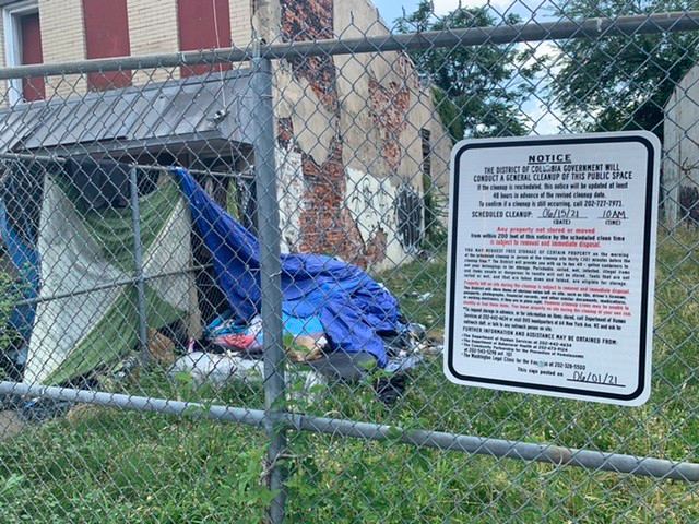 Photo of the notice sign and some tents are visible along the fence line