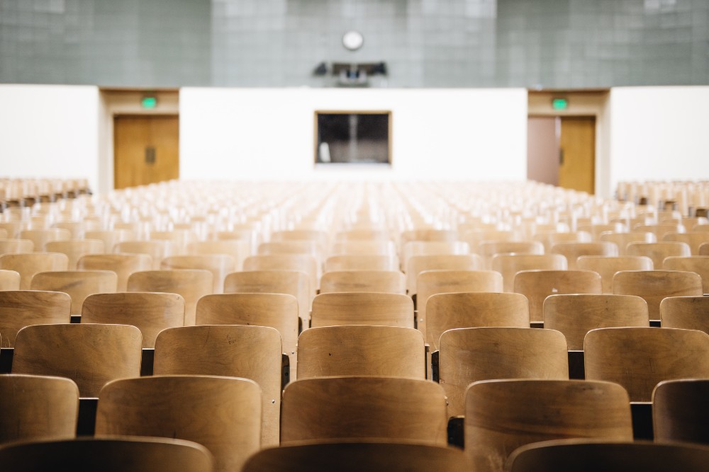 Rows of desks sit empty in a college classroom.