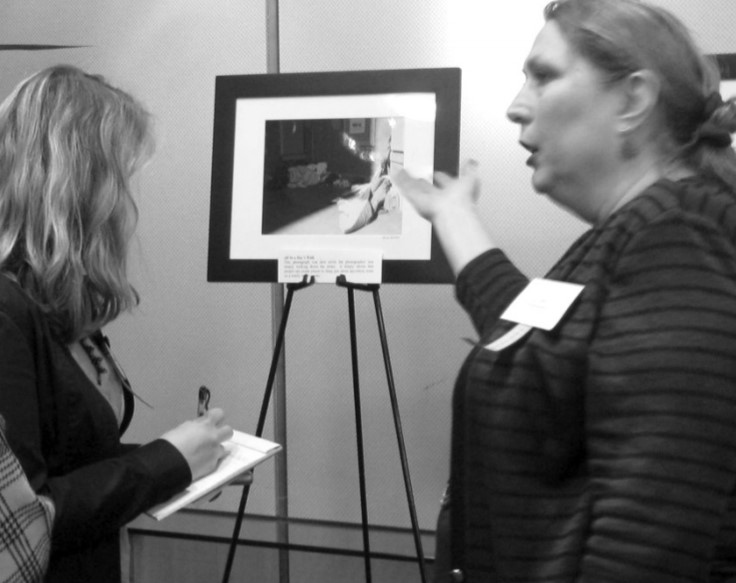 Lisa Moore speaks with attendees as she shows a photo from the exhibit