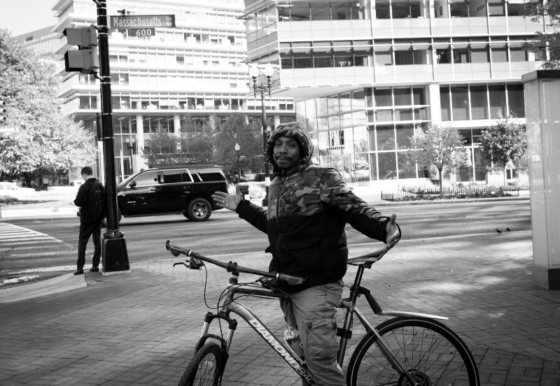 A black and white photo of a man on a bicycle with out-stretched arms