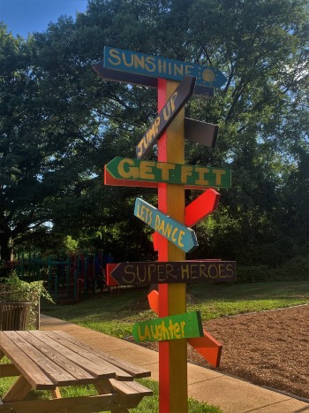 A playground sign points to various activities such as "get fit," "let's dance," and "laughter"