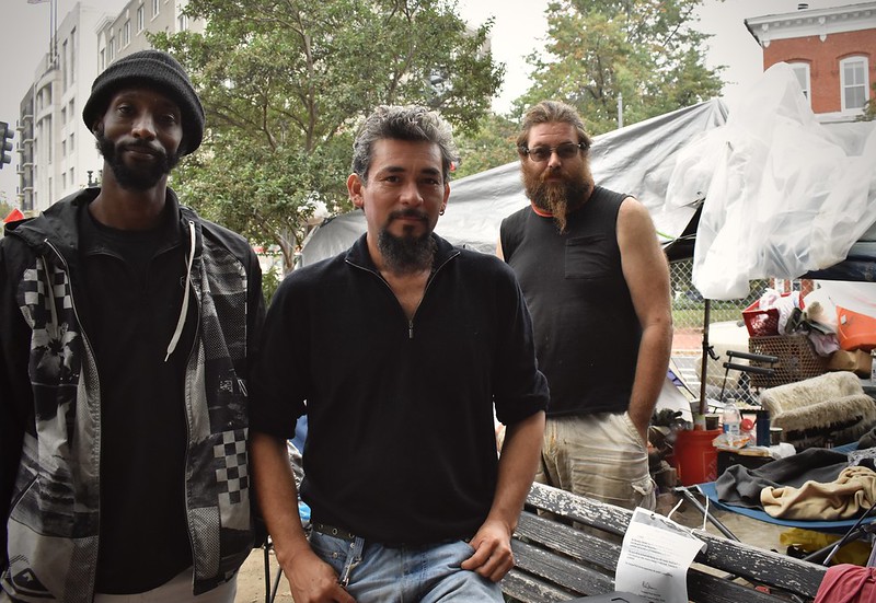Three homeless residents standing in the 3rd Street and Massachusetts Ave. encampment
