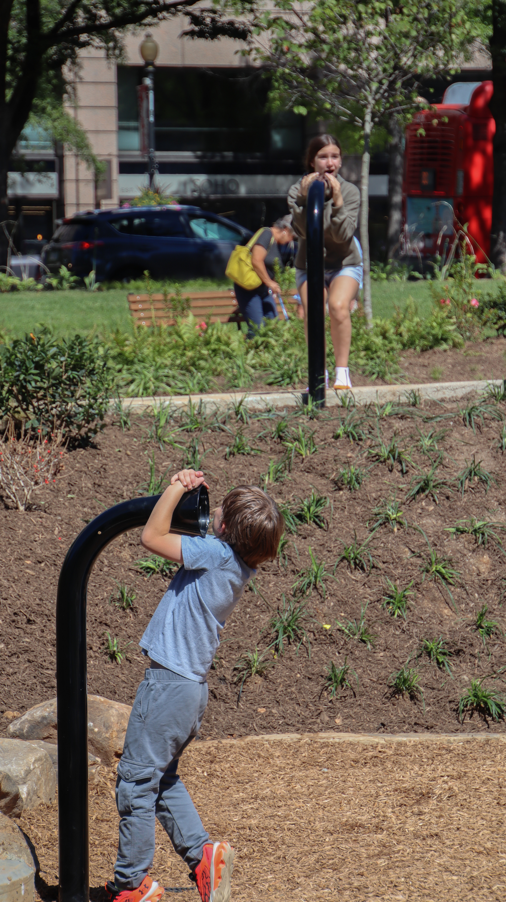 Two children speak to each other through a port-hole telephone in the kids area at newly-renovated Franklin Park.