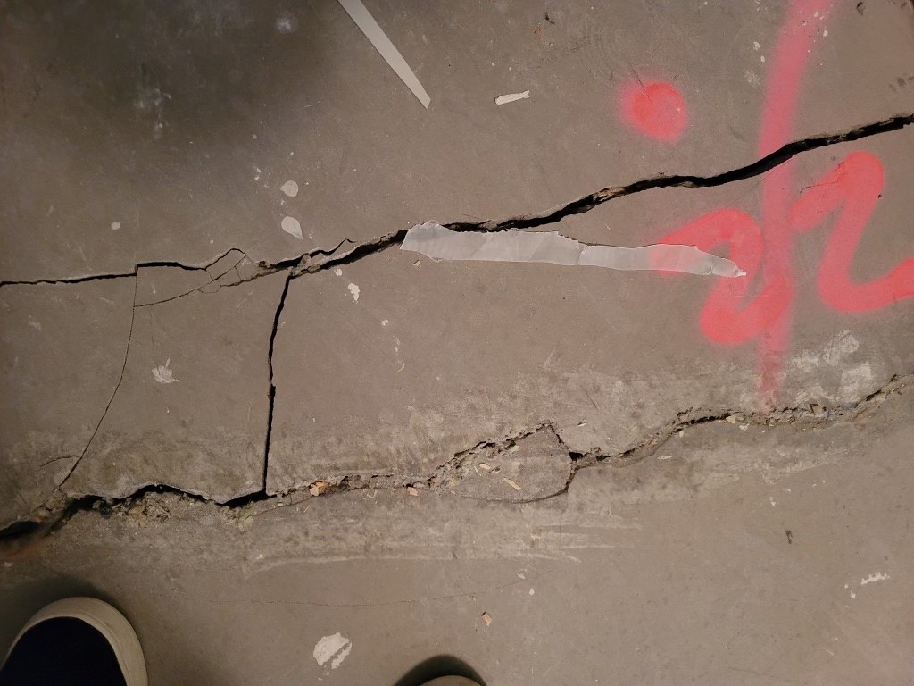 Multiple cracks run through a cement floor. 