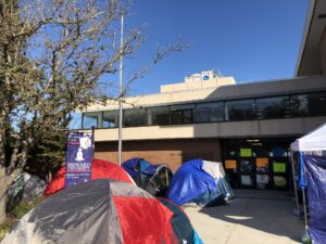 Multiple tents line up outside a building.
