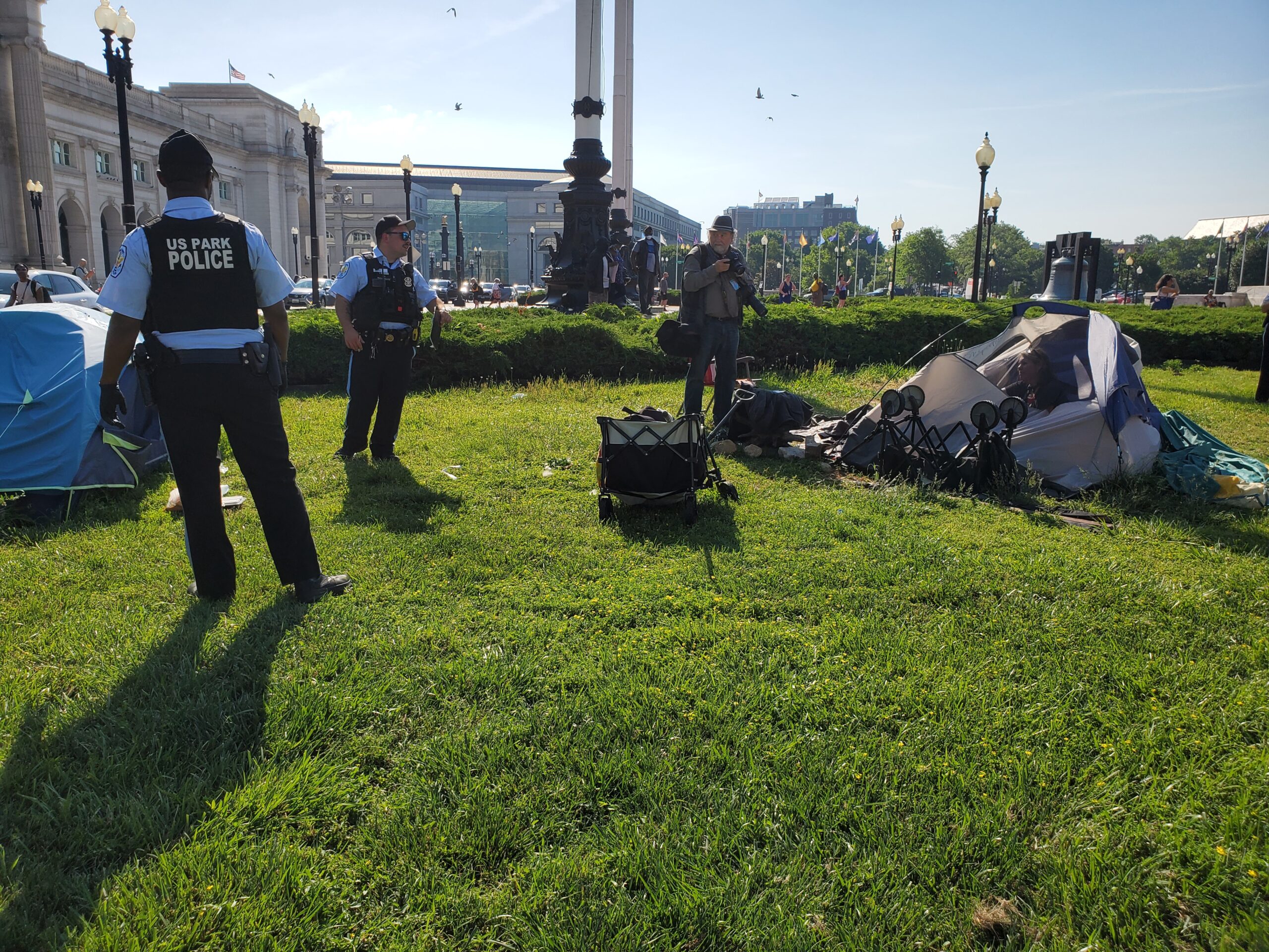 Two Park Police officers look at a tent. 