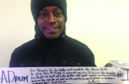 Photo of a person wearing a hat and coat holding up a ribbon with handwriting on it next to the large phrase "I have a dream..."