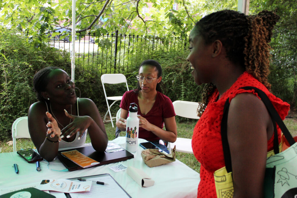 Egette Indelele (left) and Speline Irakoze (right) speak in the Take Action tent.