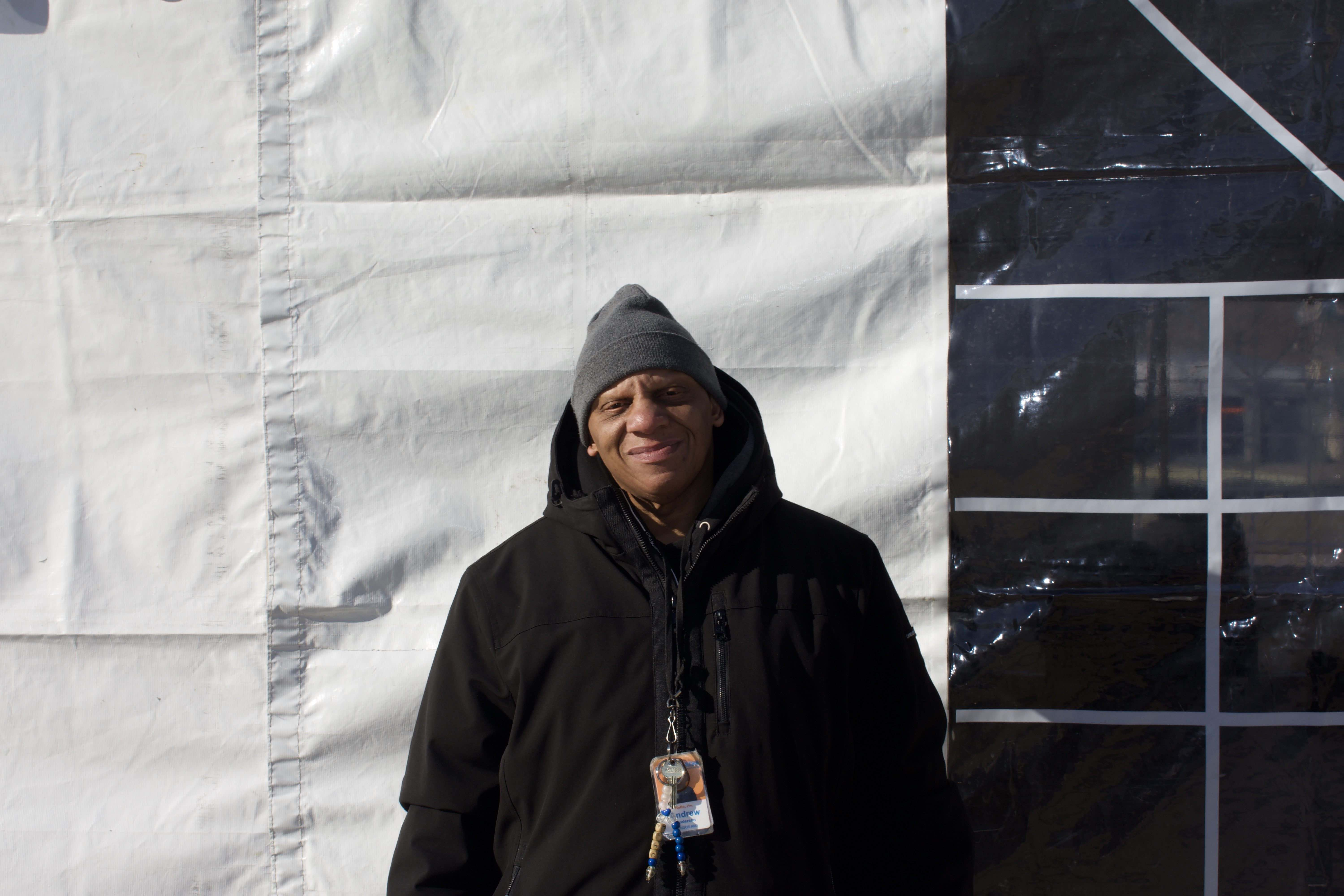 A man stands in front of a white tent. 